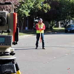 Crew member sighting through the total station on a residential street
